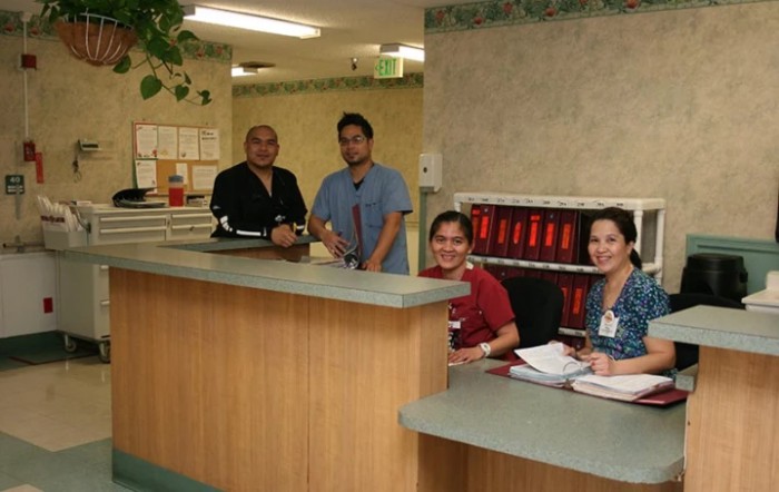 A group of healthcare workers behind a reception desk in a medical facility.