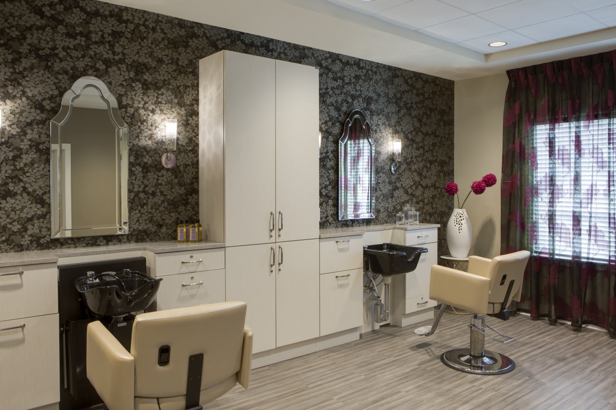 A modern hair salon interior with stylish chairs, mirrors, and cabinetry.
