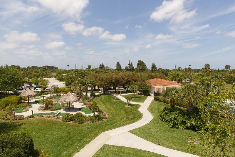 A scenic outdoor landscape with winding paths, lush greenery, and a house in the background.