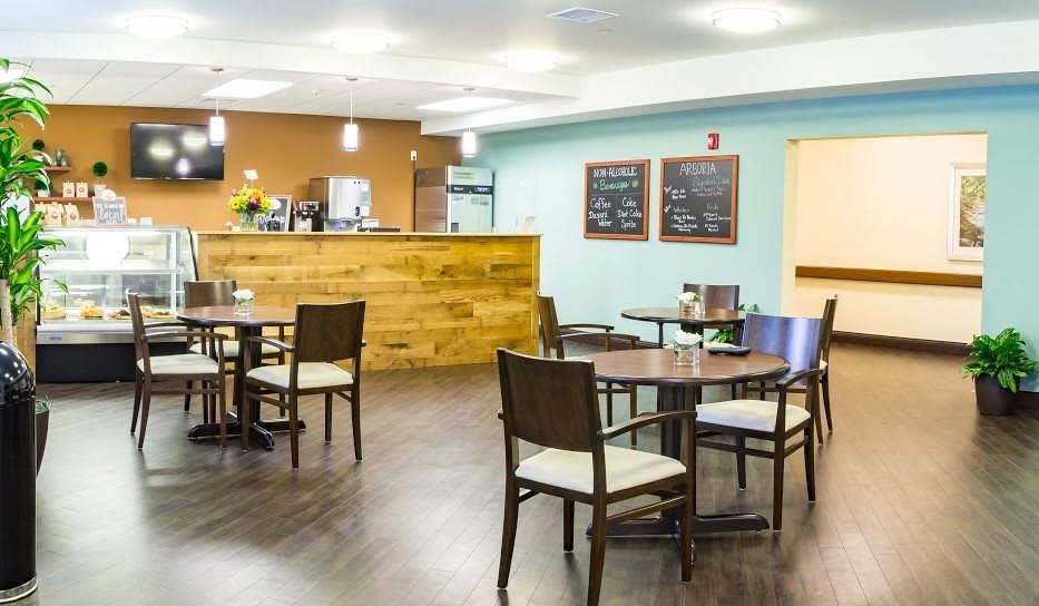 A cozy cafe interior with wooden tables and chairs, featuring a counter and menu boards.