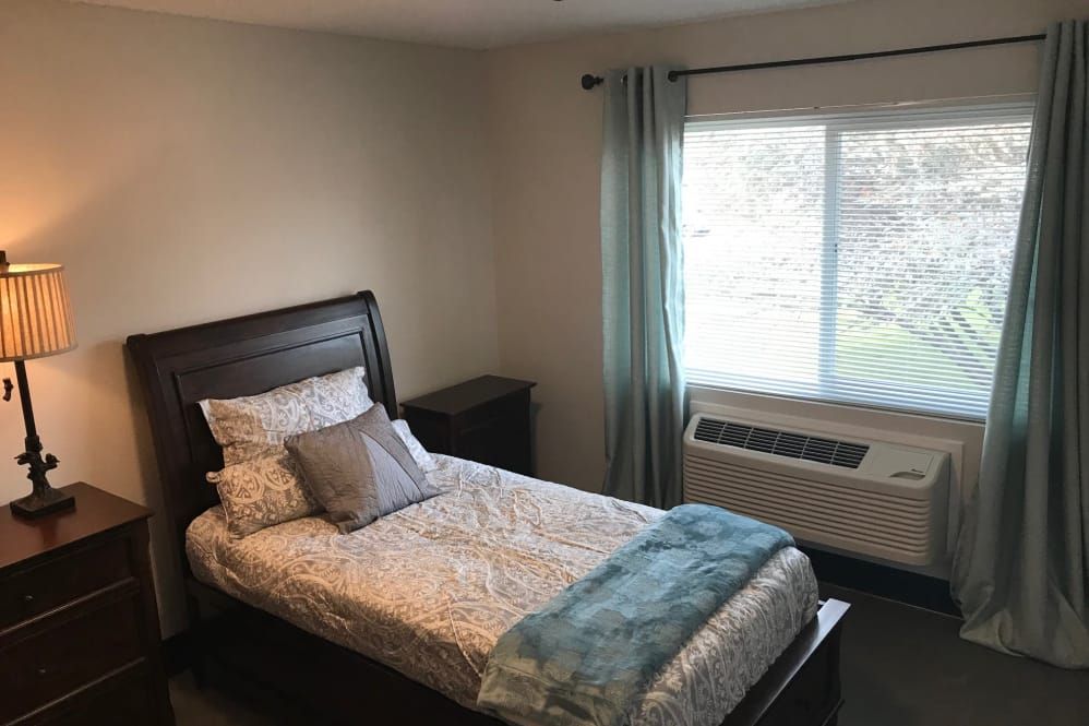 A cozy bedroom with a single bed and a window view.