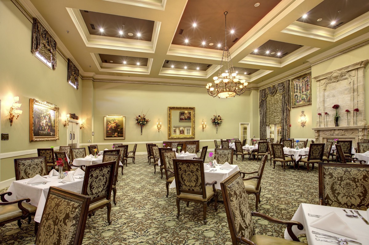 An elegant restaurant dining room with chandeliers and neatly arranged tables.