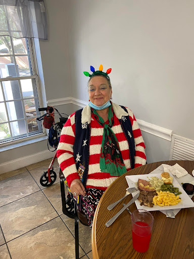 An elderly person enjoying a festive holiday meal, dressed in a colorful Christmas sweater and hat.