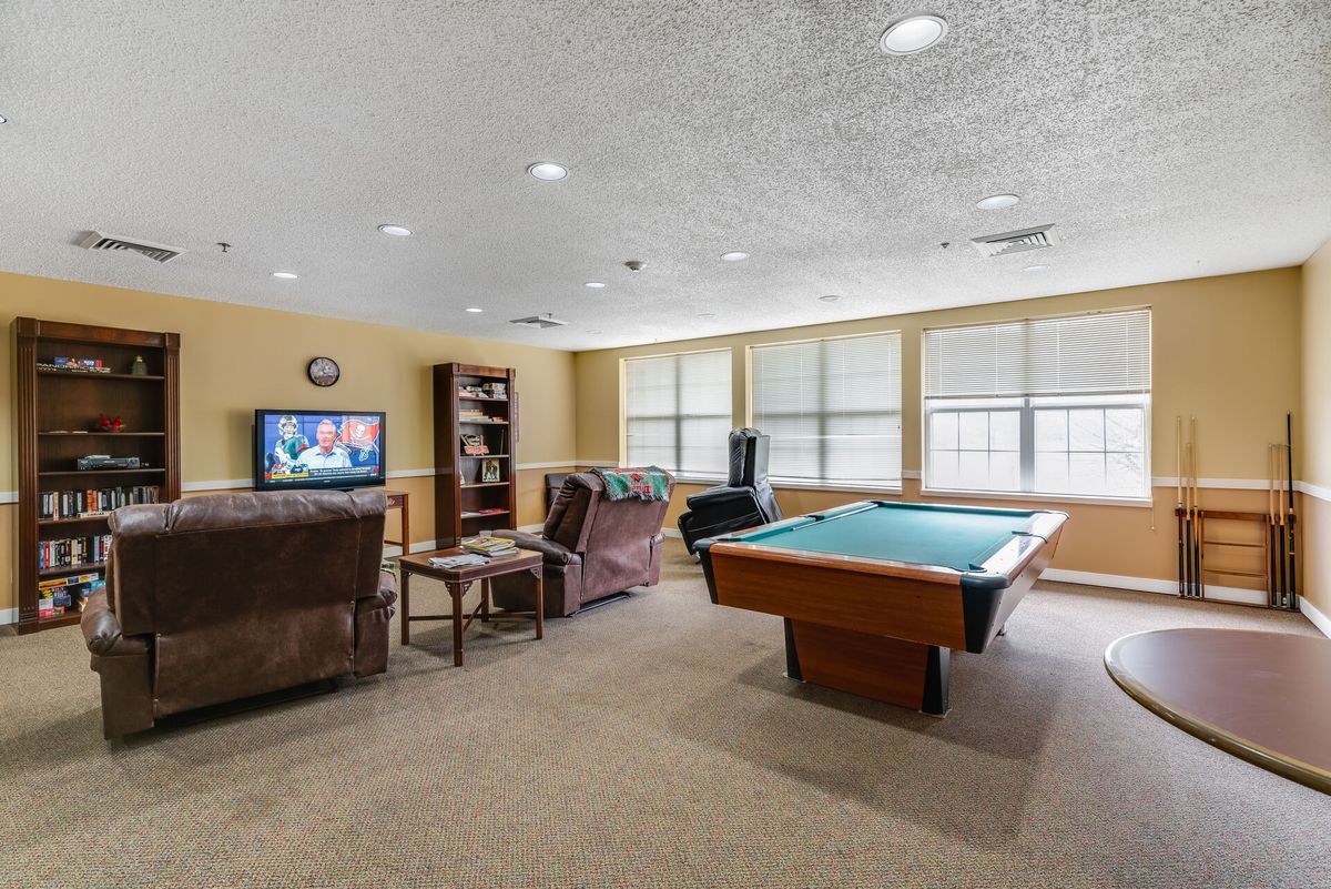 A cozy game room featuring a billiards table, television, and comfortable seating.