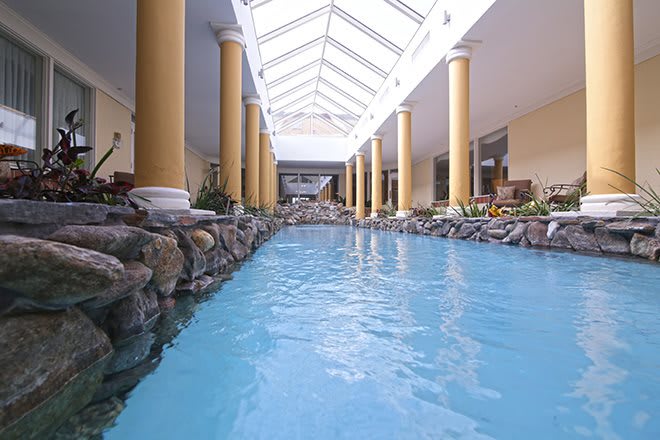 A luxurious indoor pool area with a skylight and decorative columns.