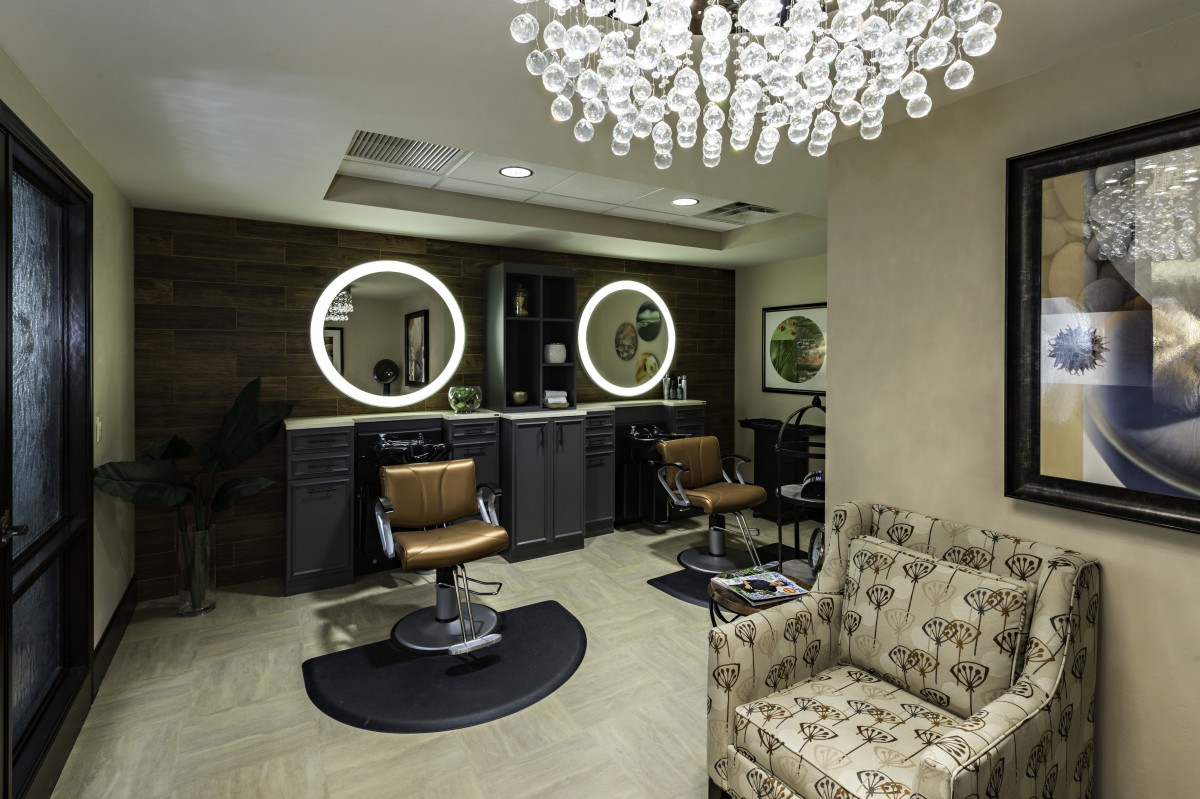 A luxurious salon interior featuring stylish chairs and illuminated mirrors.