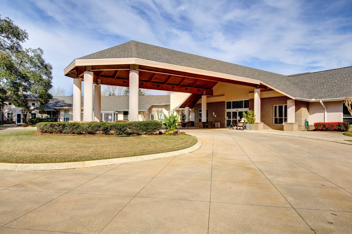 A welcoming entrance of a building with a covered driveway and landscaped surroundings.