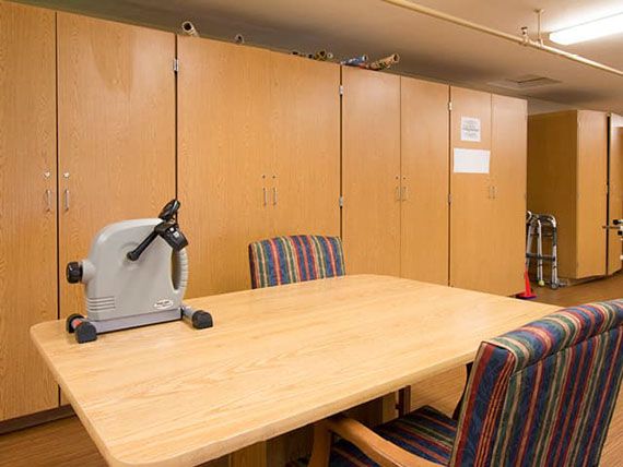 A meeting room with a wooden table, striped chairs, and exercise equipment.