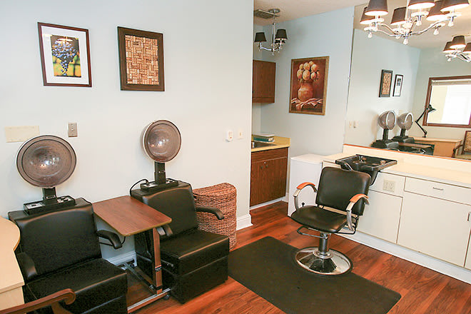 A cozy hair salon interior featuring chairs, a mirror, and wall artwork.