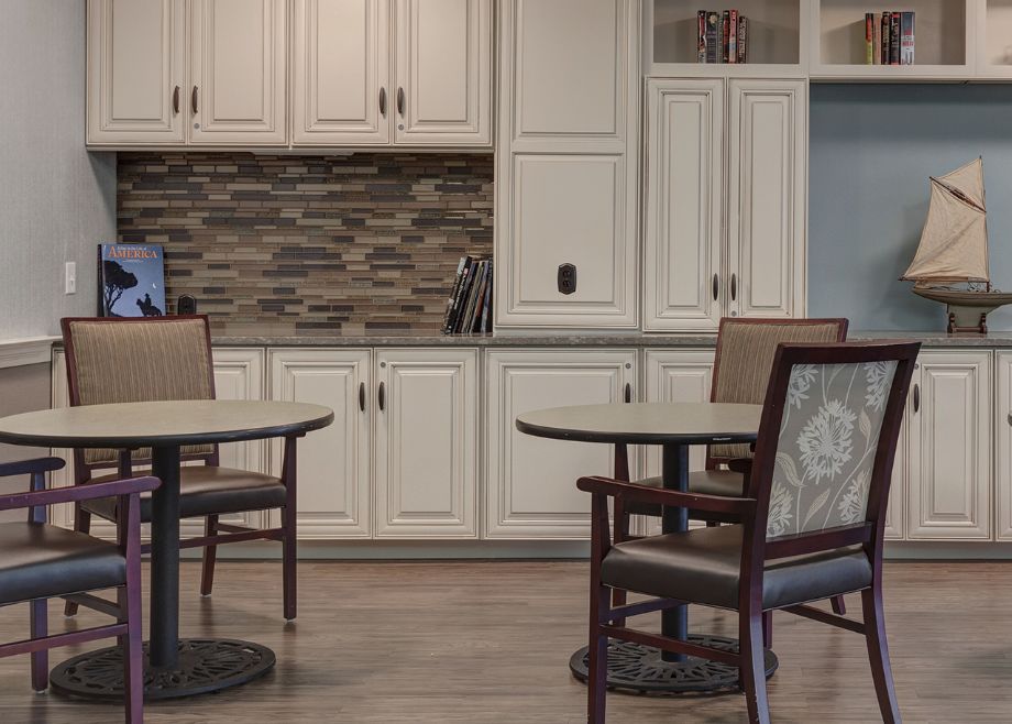 A modern kitchen interior with white cabinets and dining furniture.