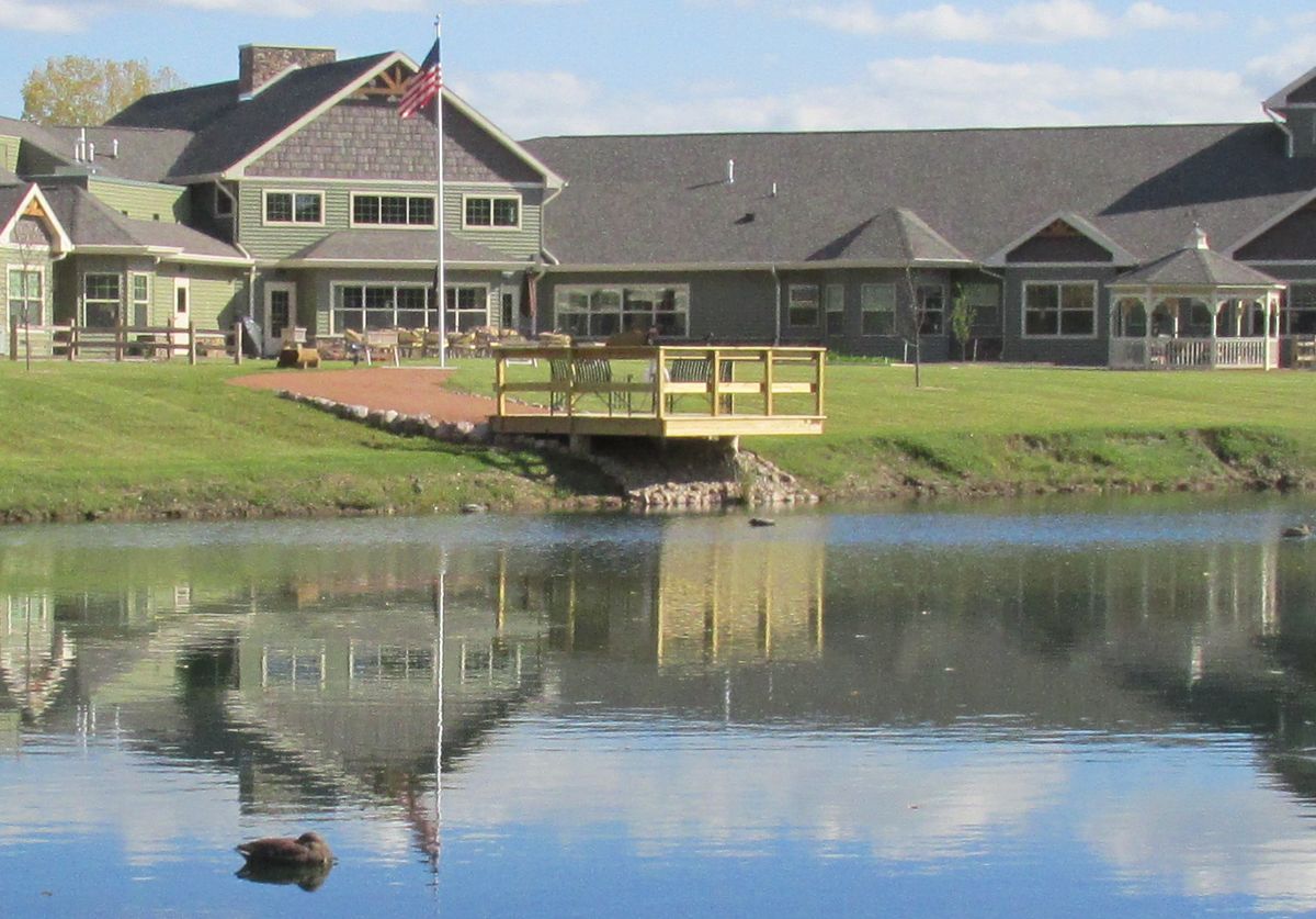 A picturesque building with a bridge over a small lake, reflecting the structure and a flag flying in the breeze.