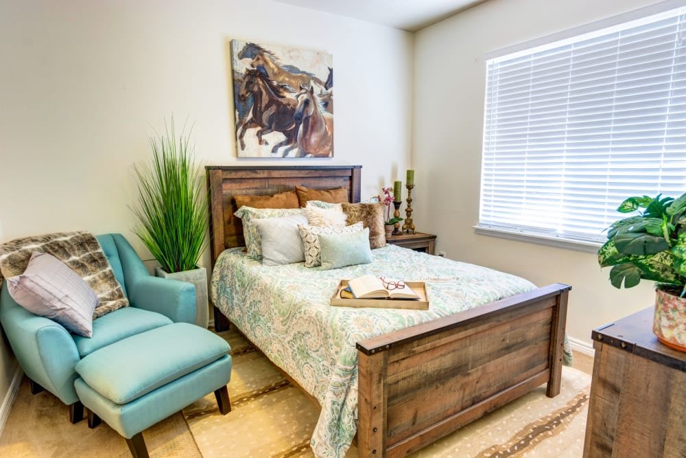 A cozy and stylish bedroom featuring a wooden bed, elegant decor, and a touch of greenery.