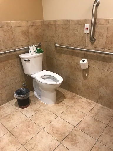 A view of a restroom featuring an accessible toilet and tiled walls.