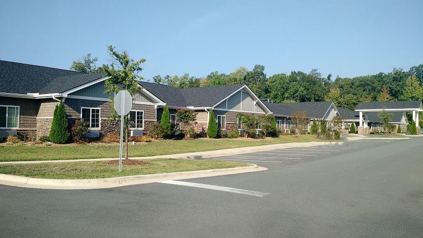 A quiet suburban neighborhood street lined with modern houses and greenery.