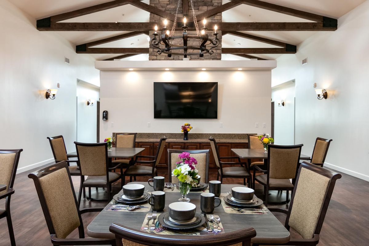 A modern dining room with a stylish table setting and wooden beam ceiling.