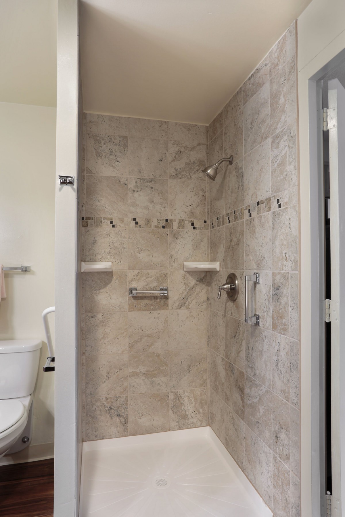A tiled bathroom shower with built-in shelves and a shower head.