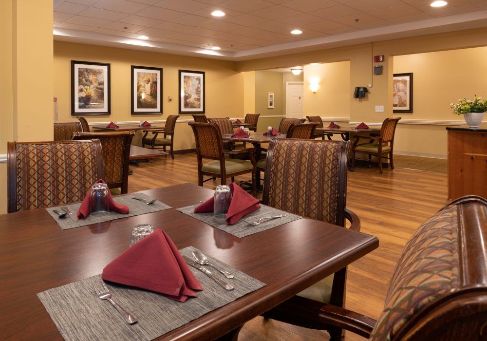 An elegantly set dining area with neatly arranged tables and comfortable chairs, featuring warm lighting and tasteful decor.