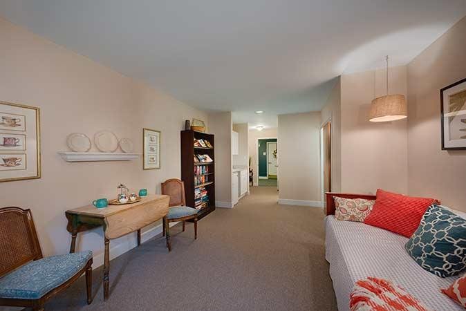 Cozy living room with a sofa, table, chairs, and a bookshelf.