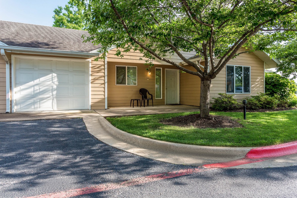 A suburban house with a garage and a tree in the front yard.