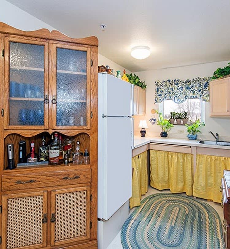 A cozy kitchen with wooden cabinets, a white refrigerator, and decorative curtains.