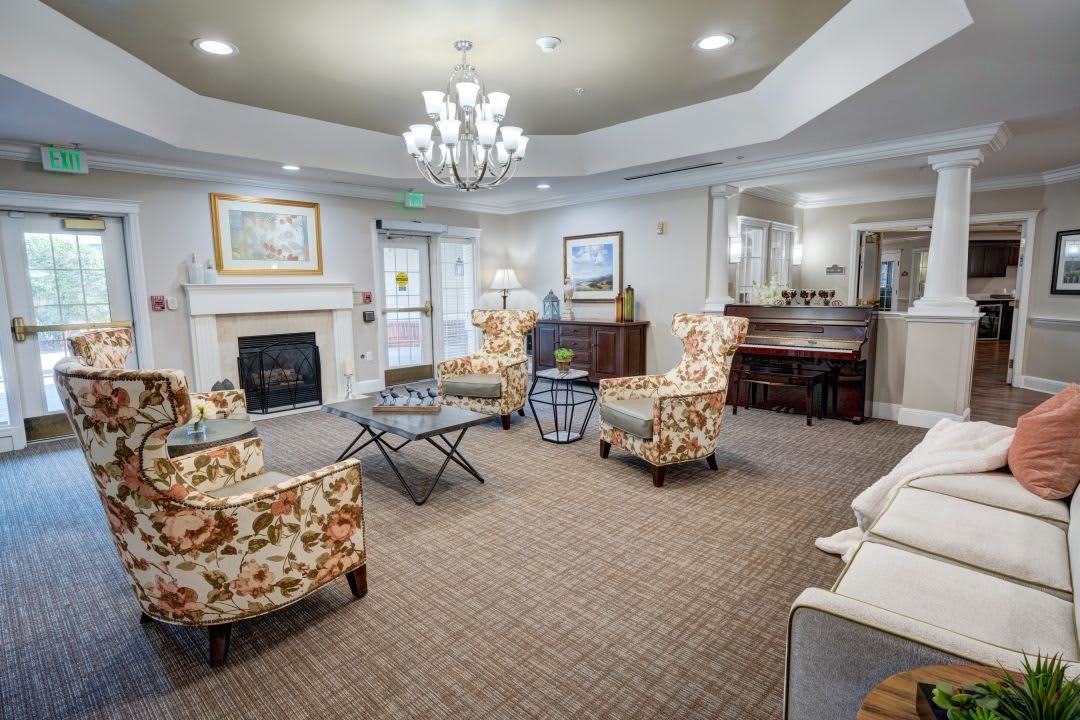 A cozy living room with elegant furnishings, featuring a chandelier and piano.