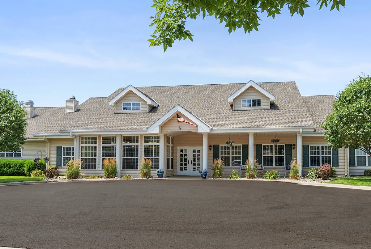 A view of a large residential building with a porch and gabled roof.