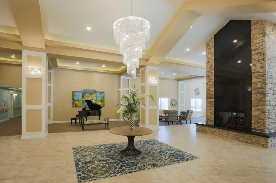 A modern lobby interior with a grand chandelier, decorative table, and a piano.