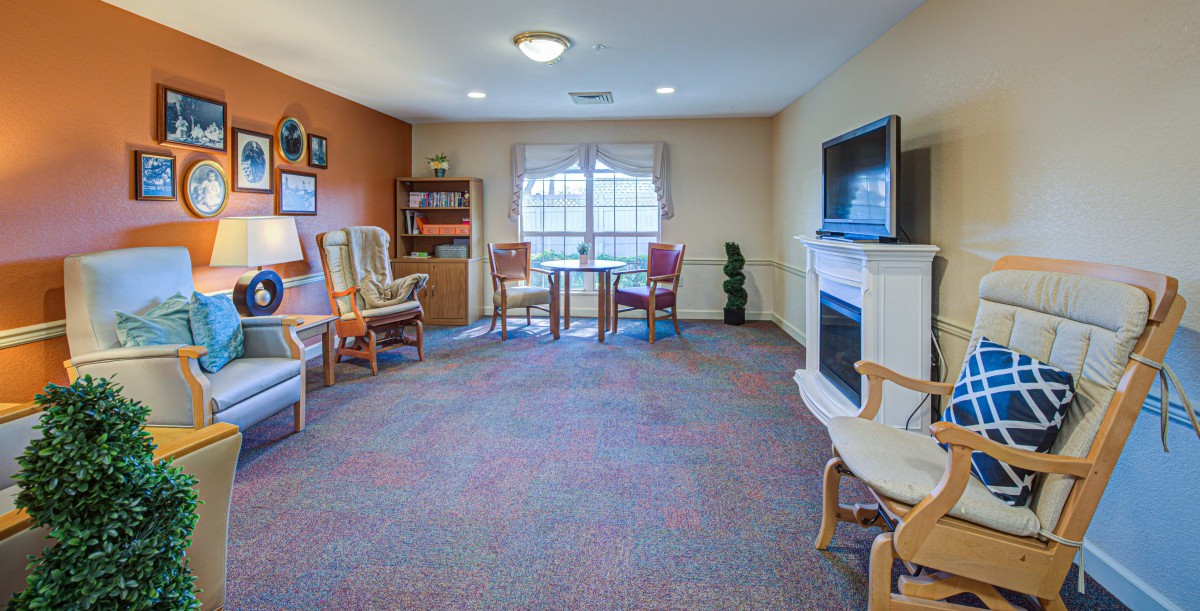 A cozy living room with chairs, a television, and a window.