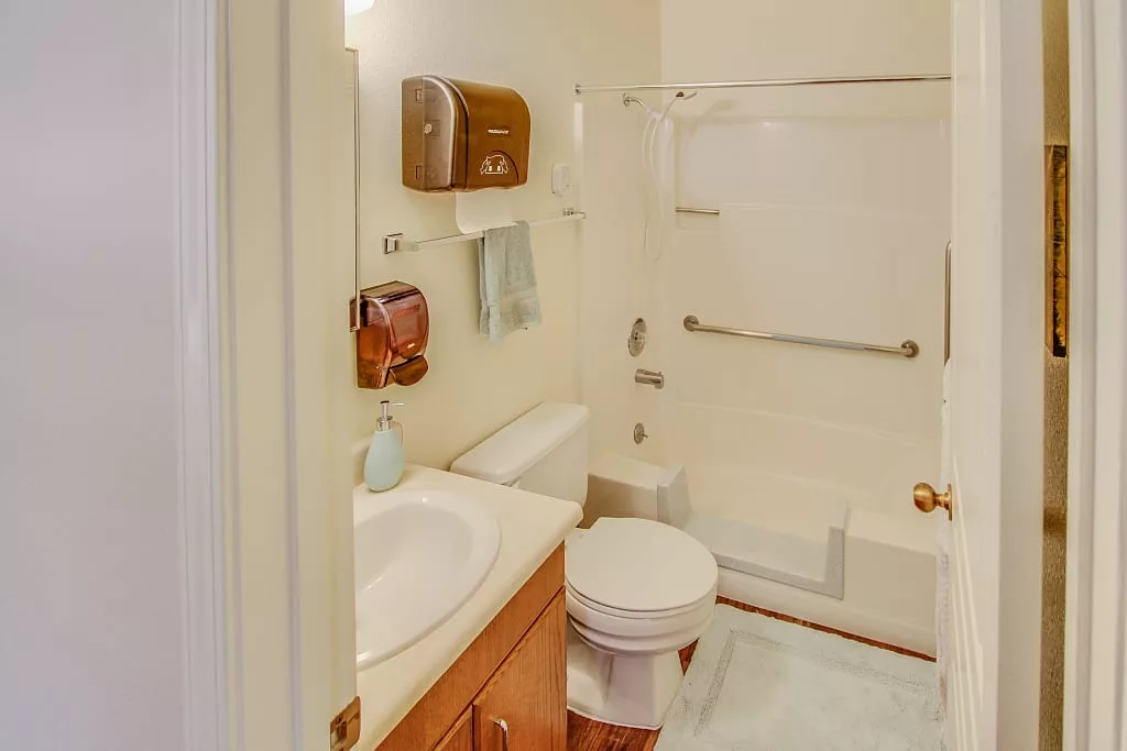 A compact bathroom featuring a sink, toilet, and shower area.