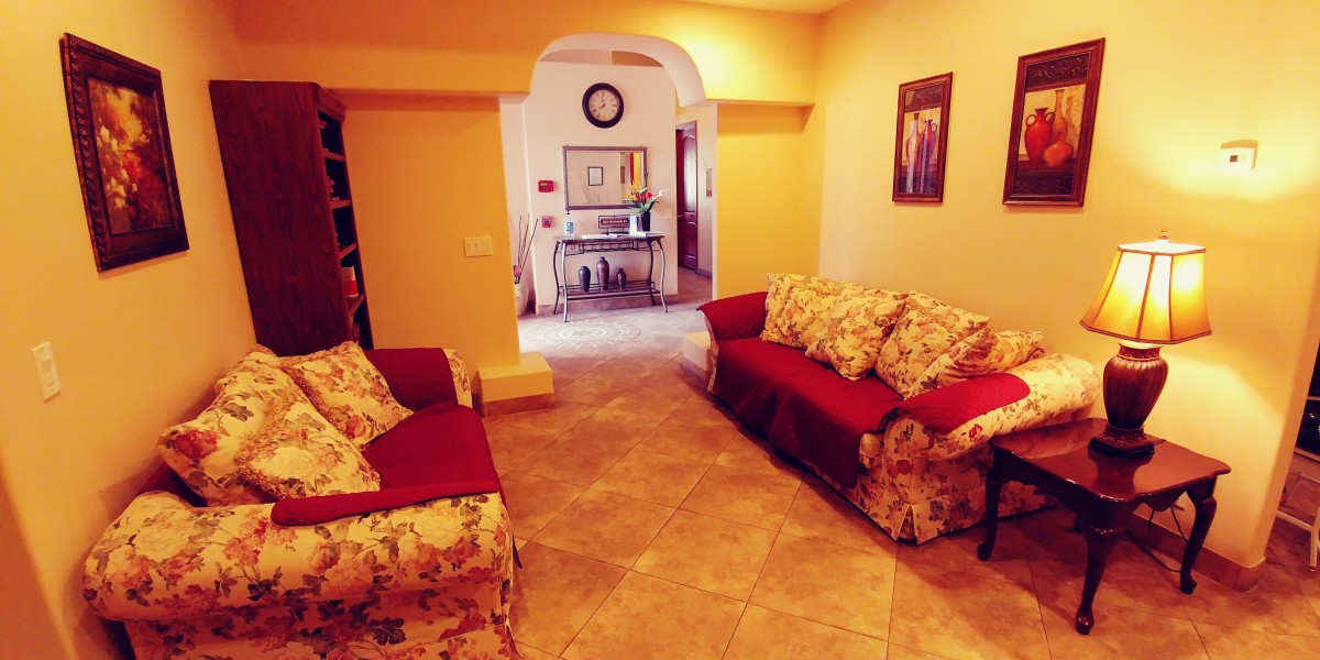 A cozy living room with floral sofas and warm lighting.