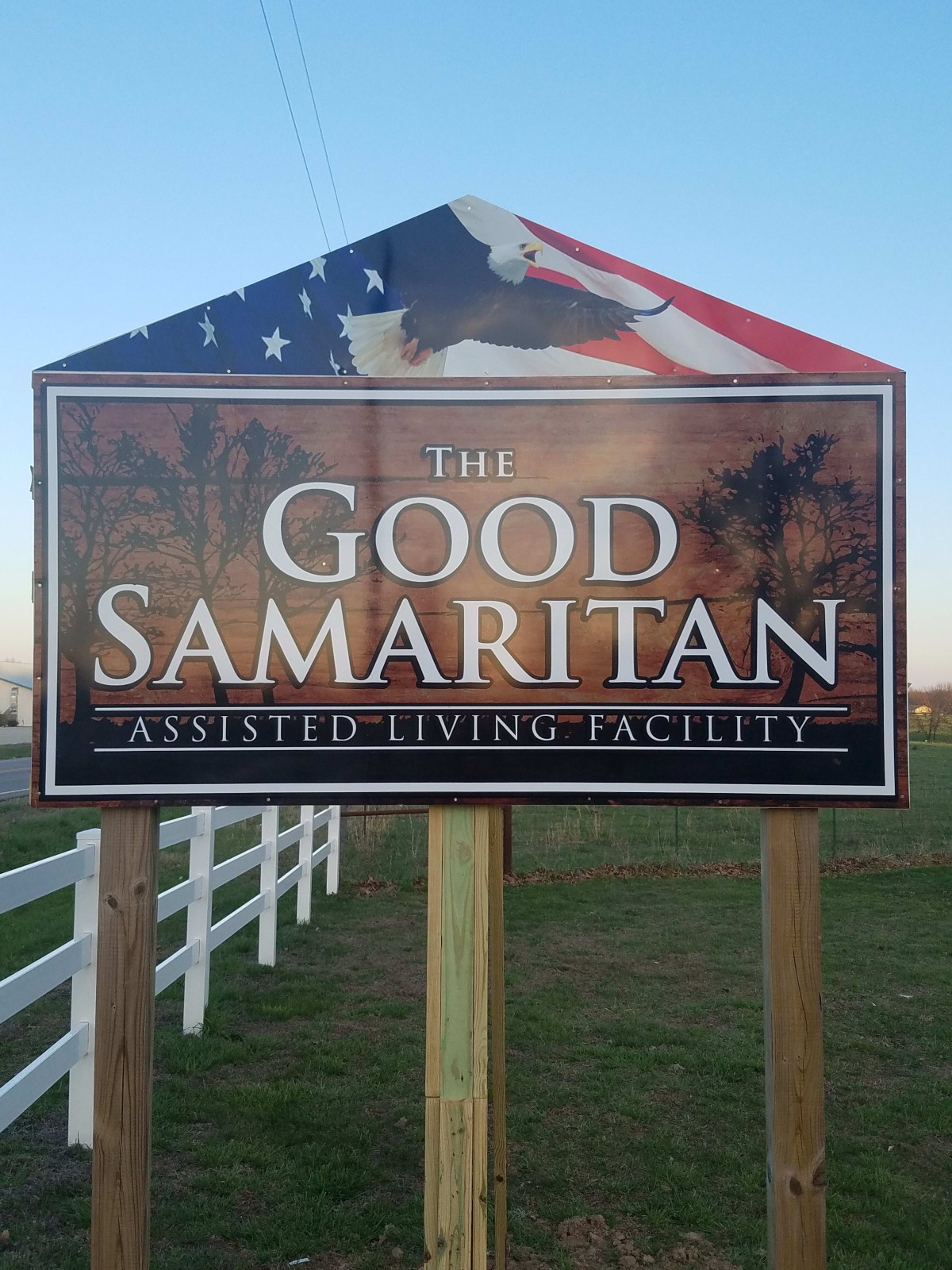 Sign for The Good Samaritan Assisted Living Facility with an American flag backdrop.