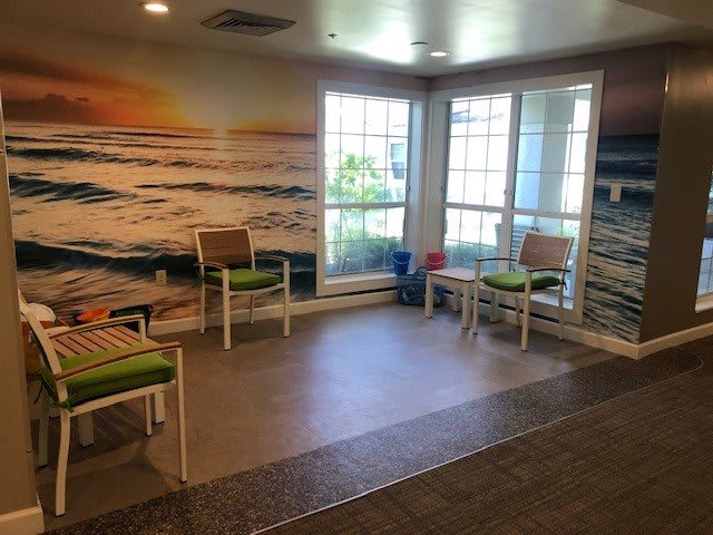 A waiting room with a beach-themed mural and seating area.
