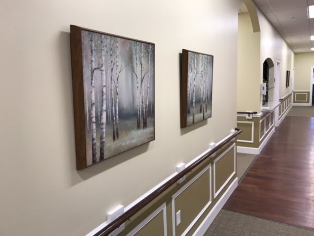 A hallway displaying two framed paintings of a woodland scene.