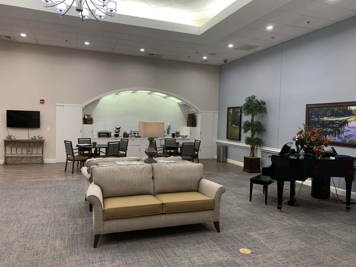 A spacious lobby with a sofa and piano, featuring elegant furniture and a meeting area.
