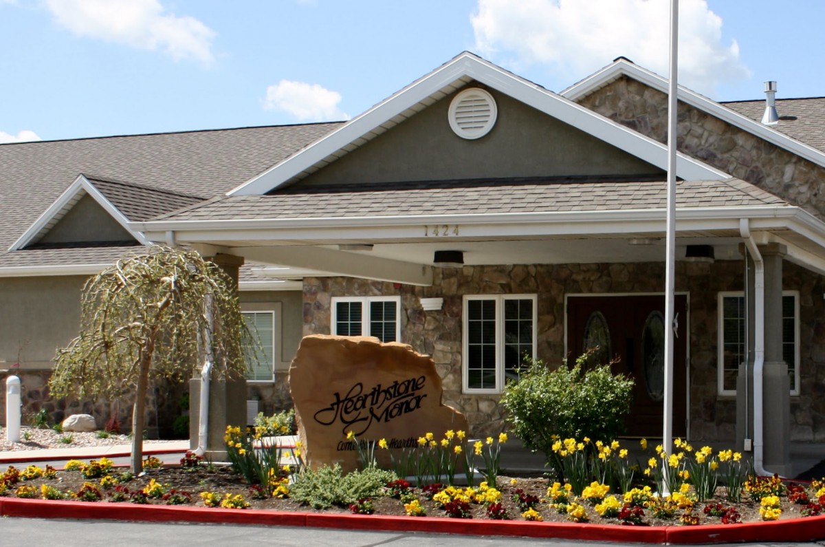 Front view of a building entrance with landscaping and a welcoming sign.