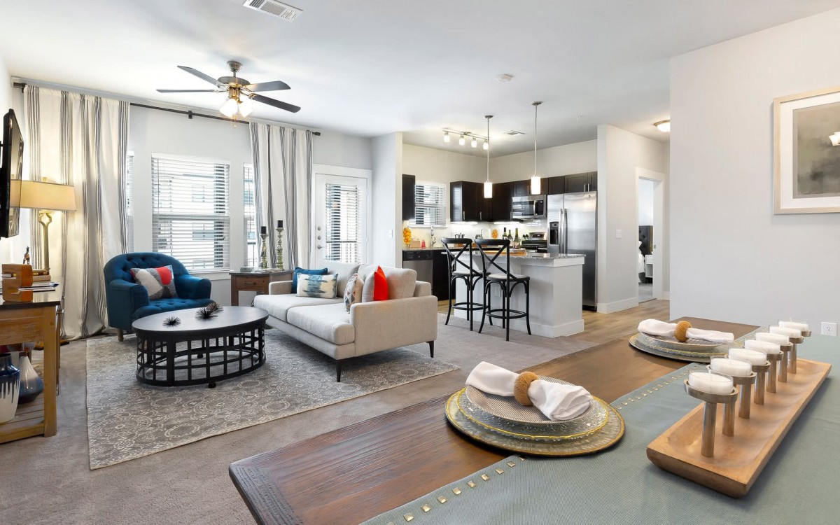 A modern open-plan living space featuring a comfortable living area, dining table, and a sleek kitchen.