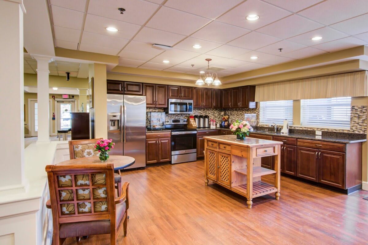 A spacious kitchen with wooden flooring and modern appliances, featuring a central island counter.
