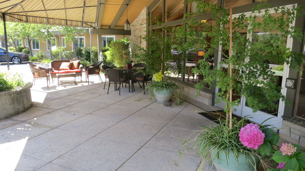 An inviting outdoor patio area with tables, chairs, and lush greenery.