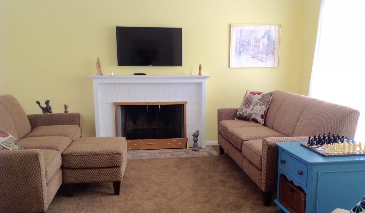 A cozy living room featuring a fireplace, wall-mounted TV, and comfortable seating.