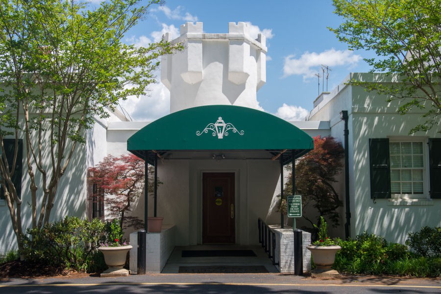 Entrance to a restaurant with a green awning and surrounding greenery.