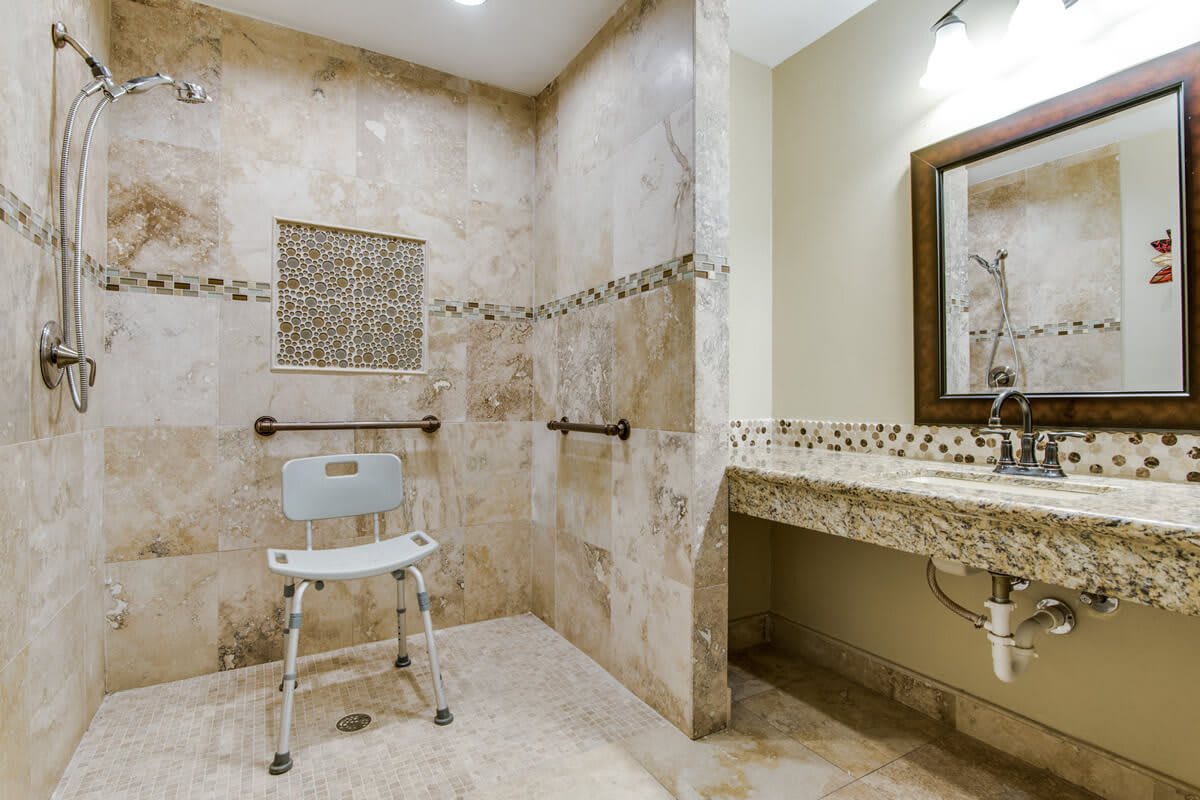 A modern, accessible bathroom with a walk-in shower and shower chair.