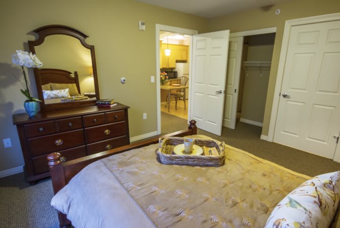 A cozy bedroom with a bed, dresser, and open closet door.