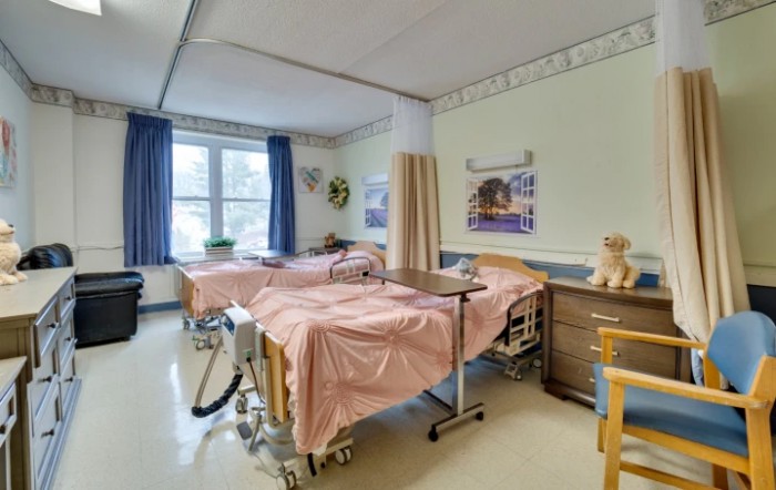 A hospital room with two beds, curtains, and medical equipment.