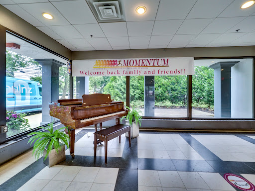 A beautifully designed lobby featuring a grand piano and lush plants, illuminated by natural light from large windows.