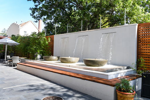 A serene outdoor fountain featuring three concrete bowls, creating a tranquil ambiance with flowing water.