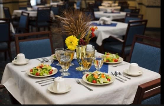 A beautifully set dining table with salads, glasses, and a floral centerpiece in a restaurant.