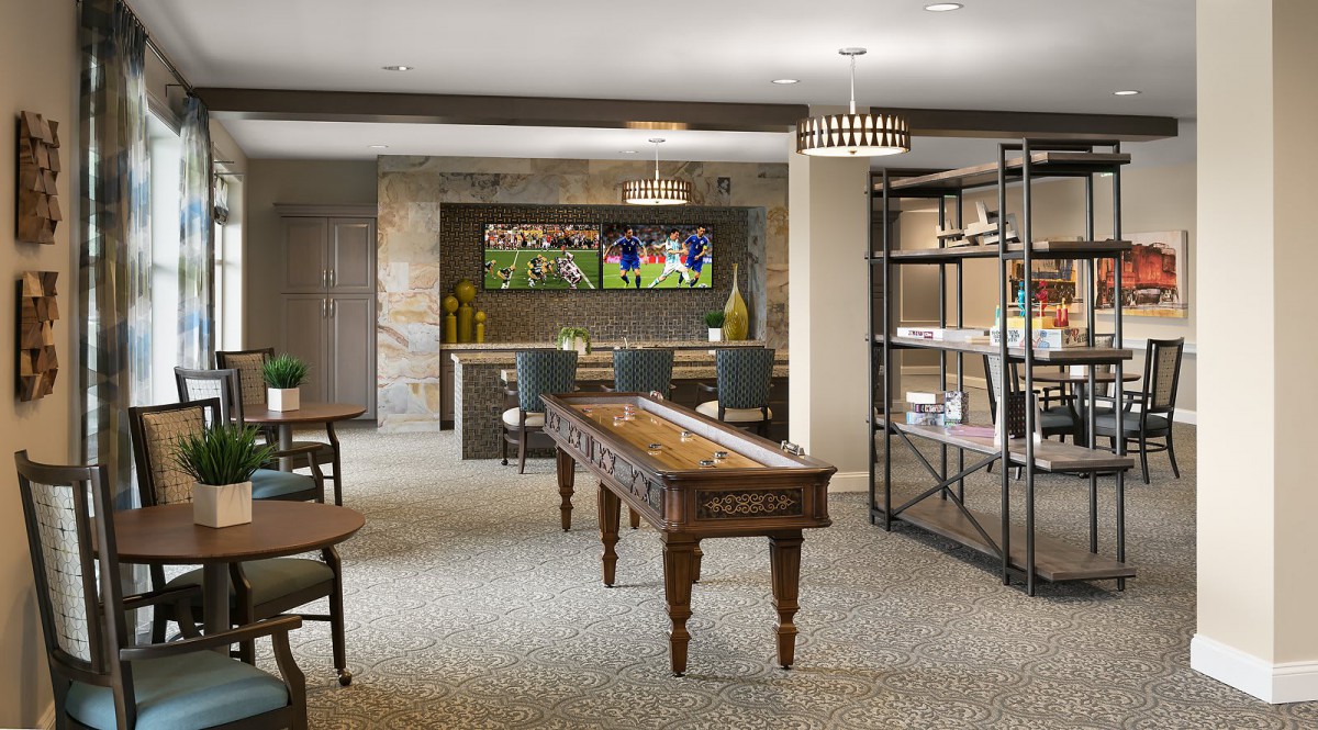 A modern game room featuring a shuffleboard table, seating area, and stylish shelves.