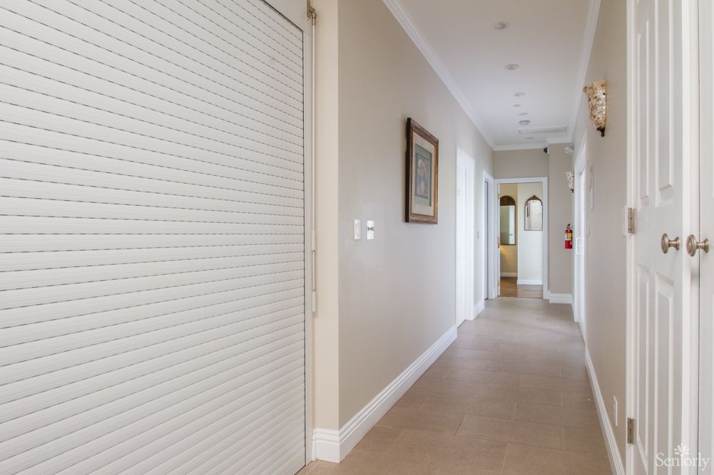 A modern hallway with light walls and a smooth floor, featuring closed doors and framed artwork.
