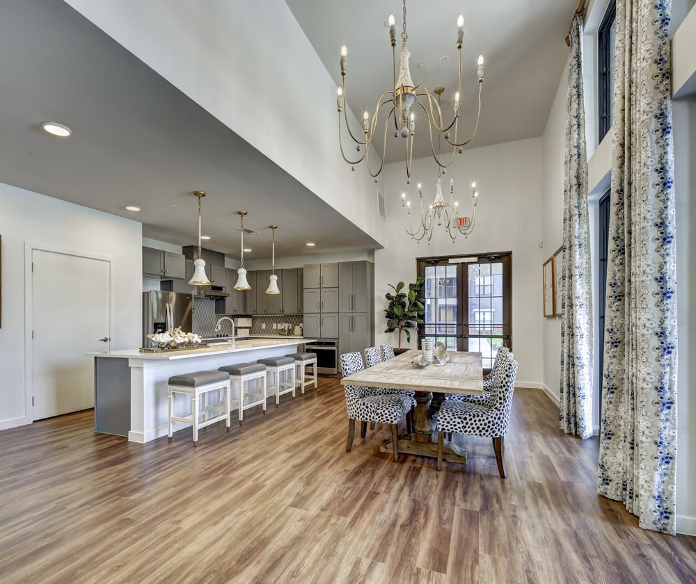 A spacious, modern kitchen and dining area with an open floor plan, featuring a large island counter, bar stools, and a beautiful chandelier.