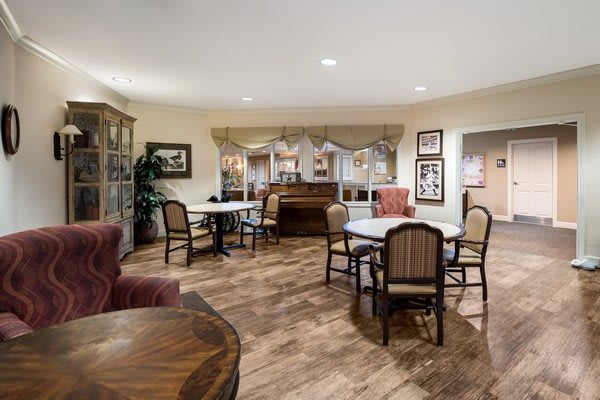 A cozy dining area with multiple tables and chairs, warm lighting, and decorative elements.